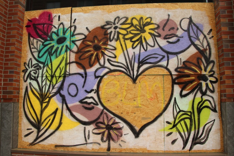 A colorful spray painted mural containing flowers, a woman's face, and hearts.