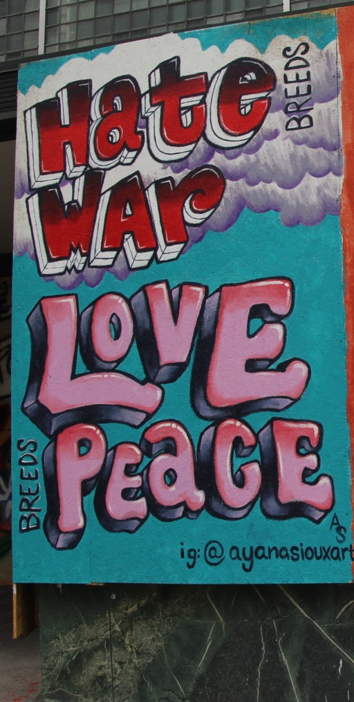 A blue mural with clouds and the words "Hate breeds war" and "Love breeds peace."