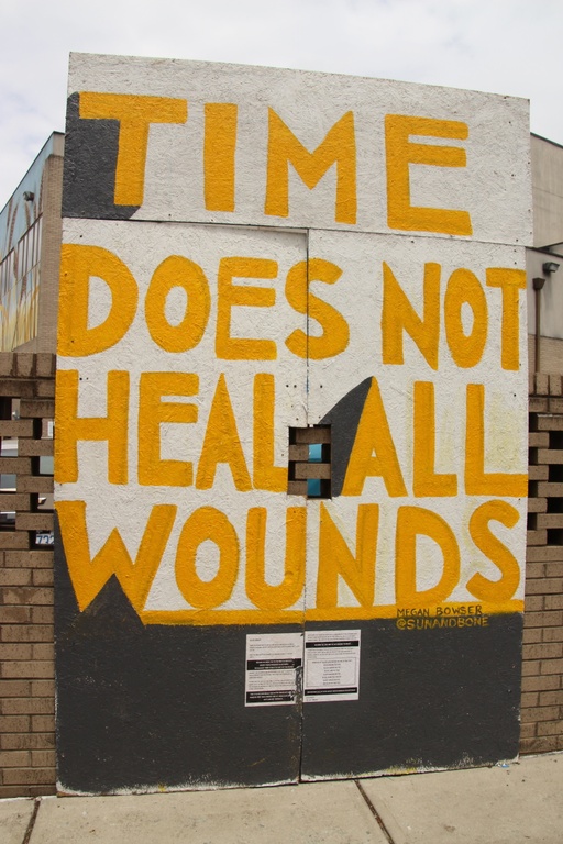A white background with the words "time does not heal all wounds" painted in yellow.