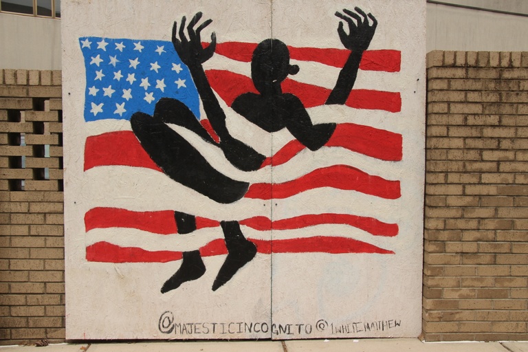 The silhouette of a black person tangled in the American flag. 