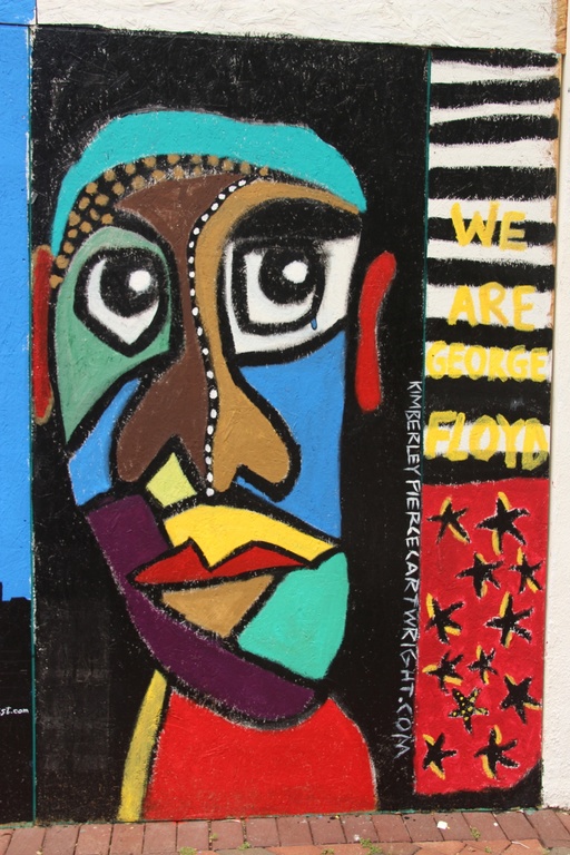 A man's face made up of colorful geometric shapes with a single tear in his eye with the words "we are George Floyd."