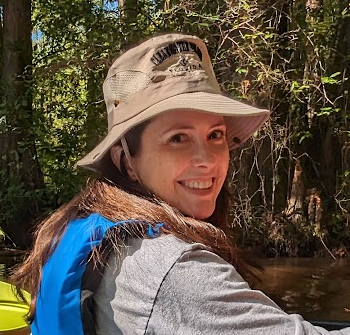 Barbara by a river in a hat and life jacket